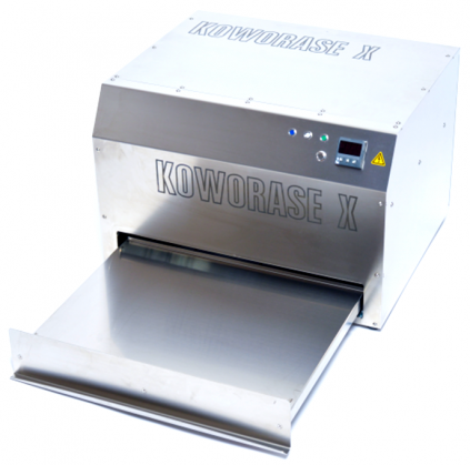 Un petit contenant métallique portant l’étiquette « Koworase X » sur son extérieur, utilisé pour effacer les films numériques (plaques d’imagerie), avec une table d’alimentation dépassant à l’avant.