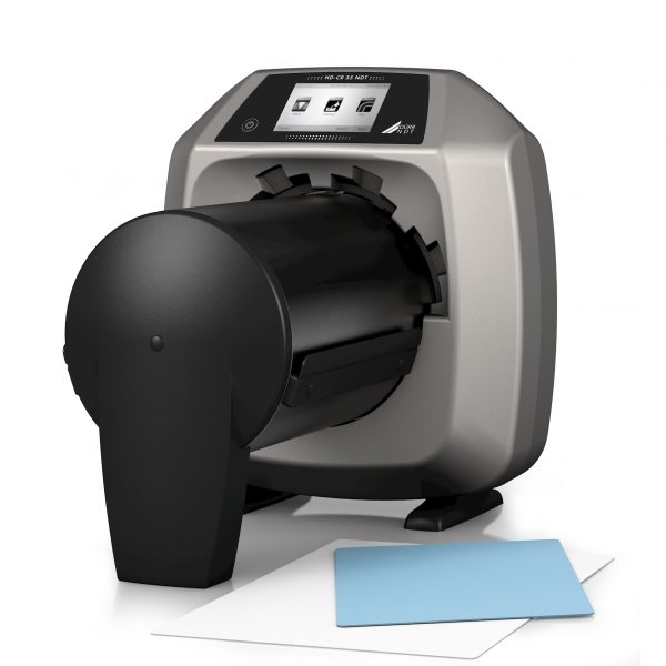 A computed radiography scanner featuring a sheet of paper resting next to it.