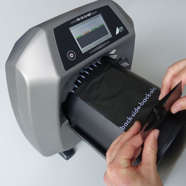 A person manipulates a computed radiography scanner